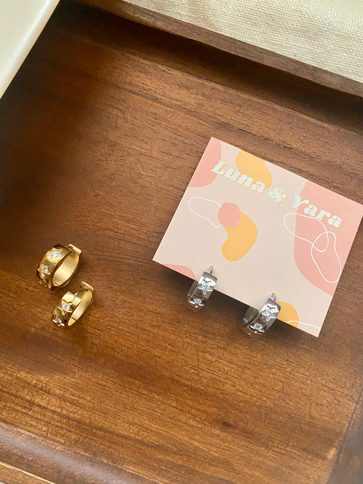 Gold and silver rings on a wooden surface with a branded card.