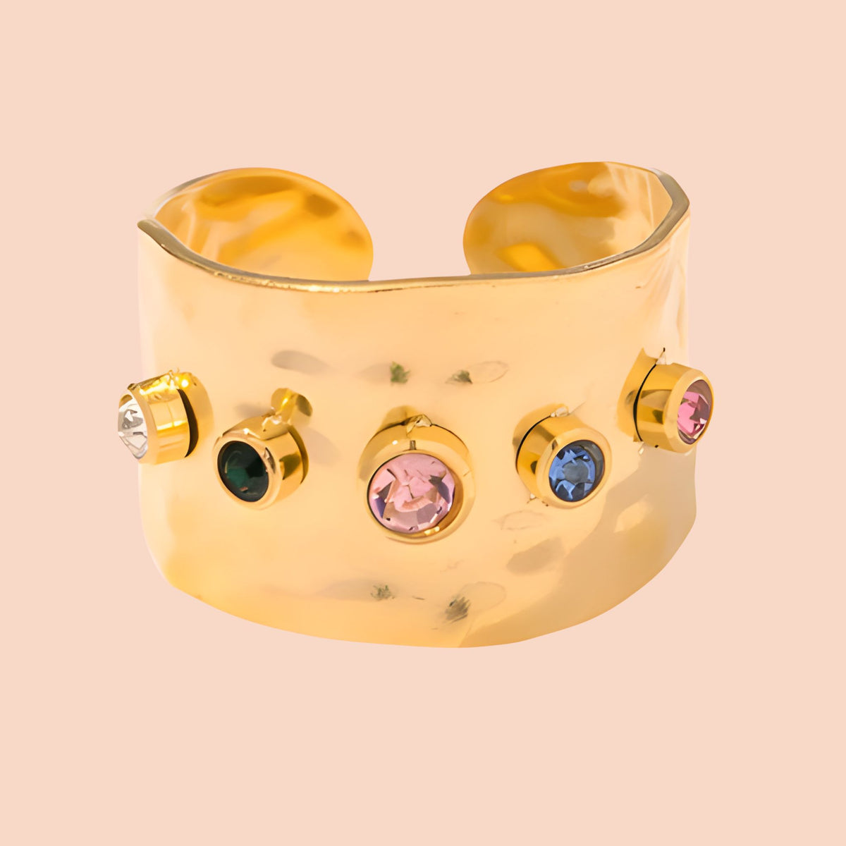 Gold ring with colorful gemstones on a beige background