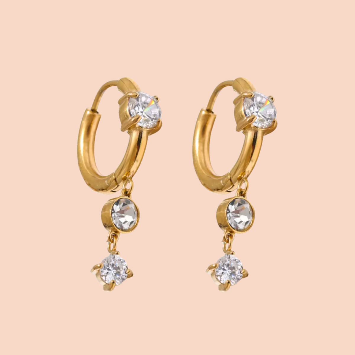 Gold hoop earrings with crystal drops on a beige background