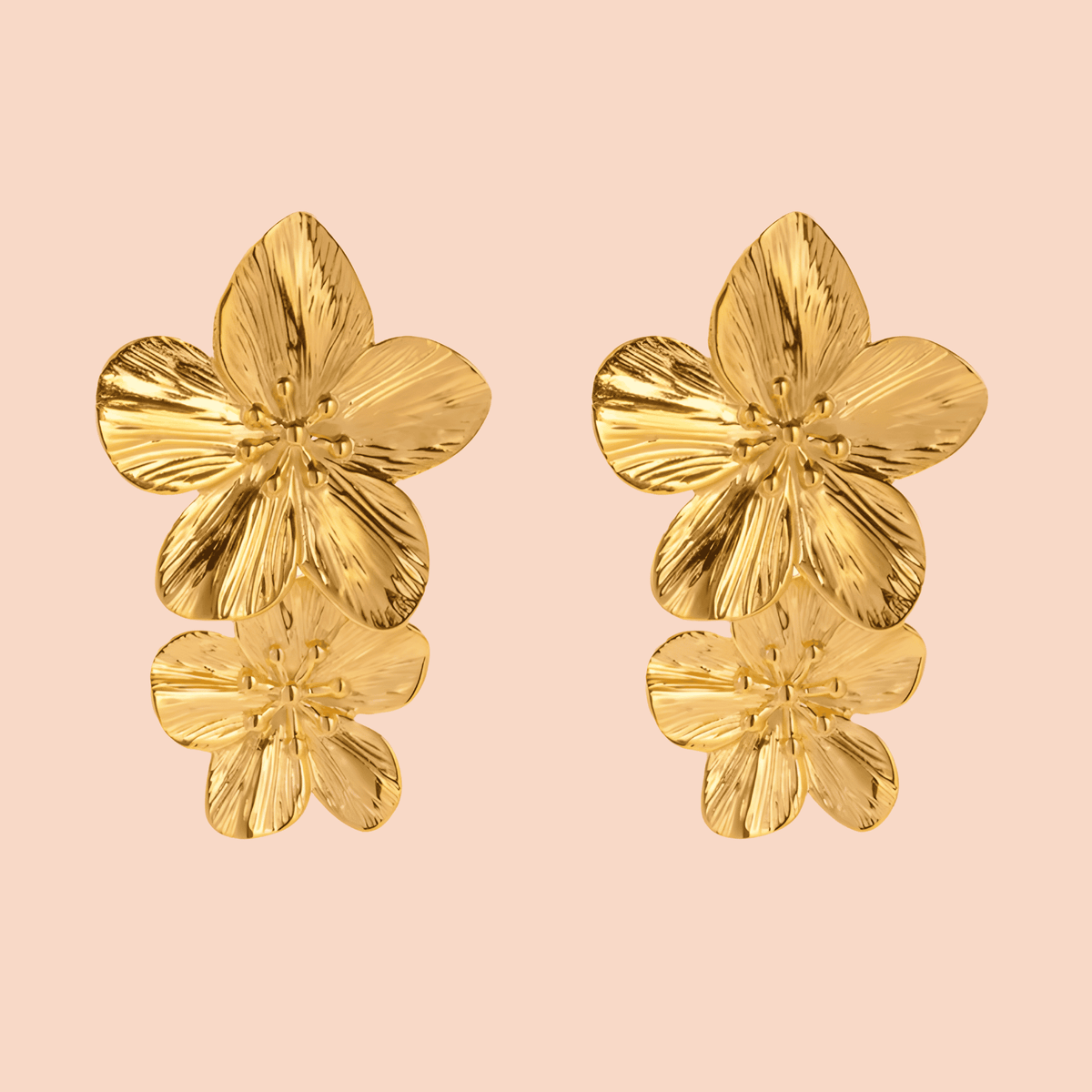 Gold floral earrings on a pink background