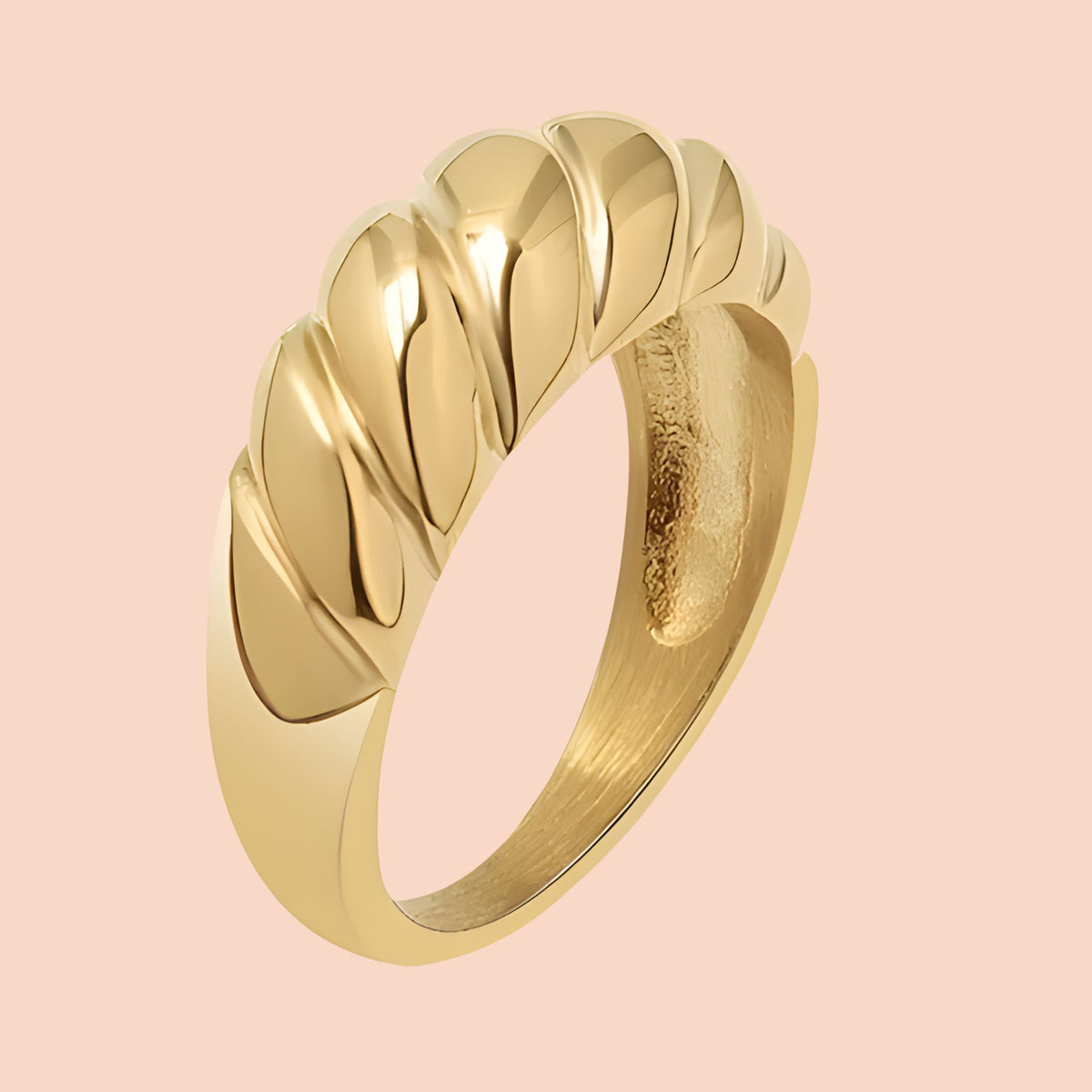 Gold ring with a textured design on a pink background