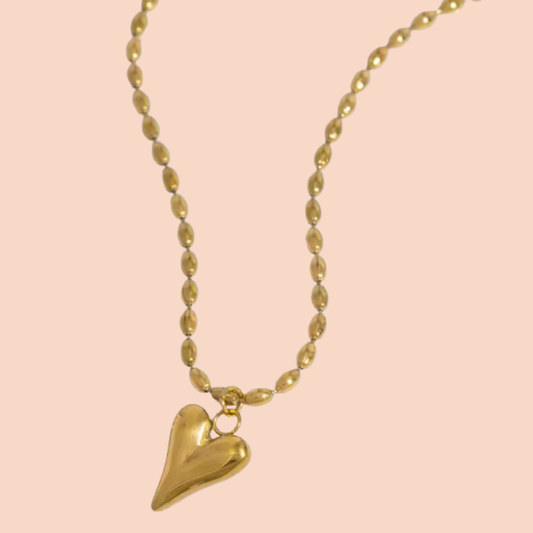 Gold heart-shaped pendant necklace on a pink background