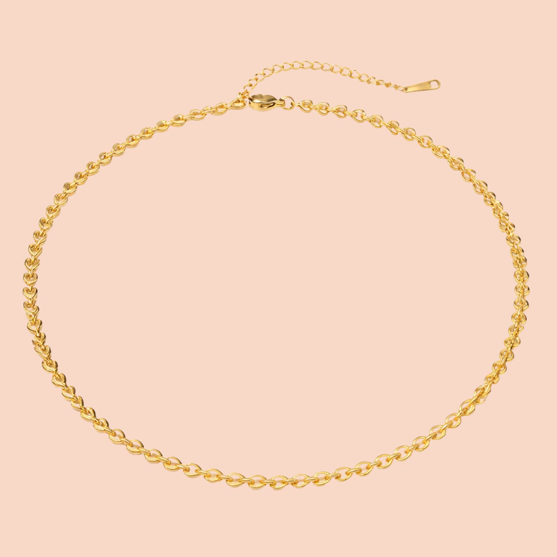 Gold chain necklace on a pink background