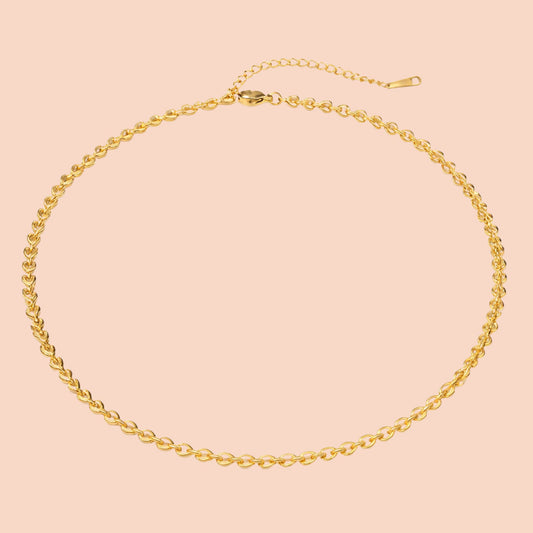 Gold chain necklace on a pink background