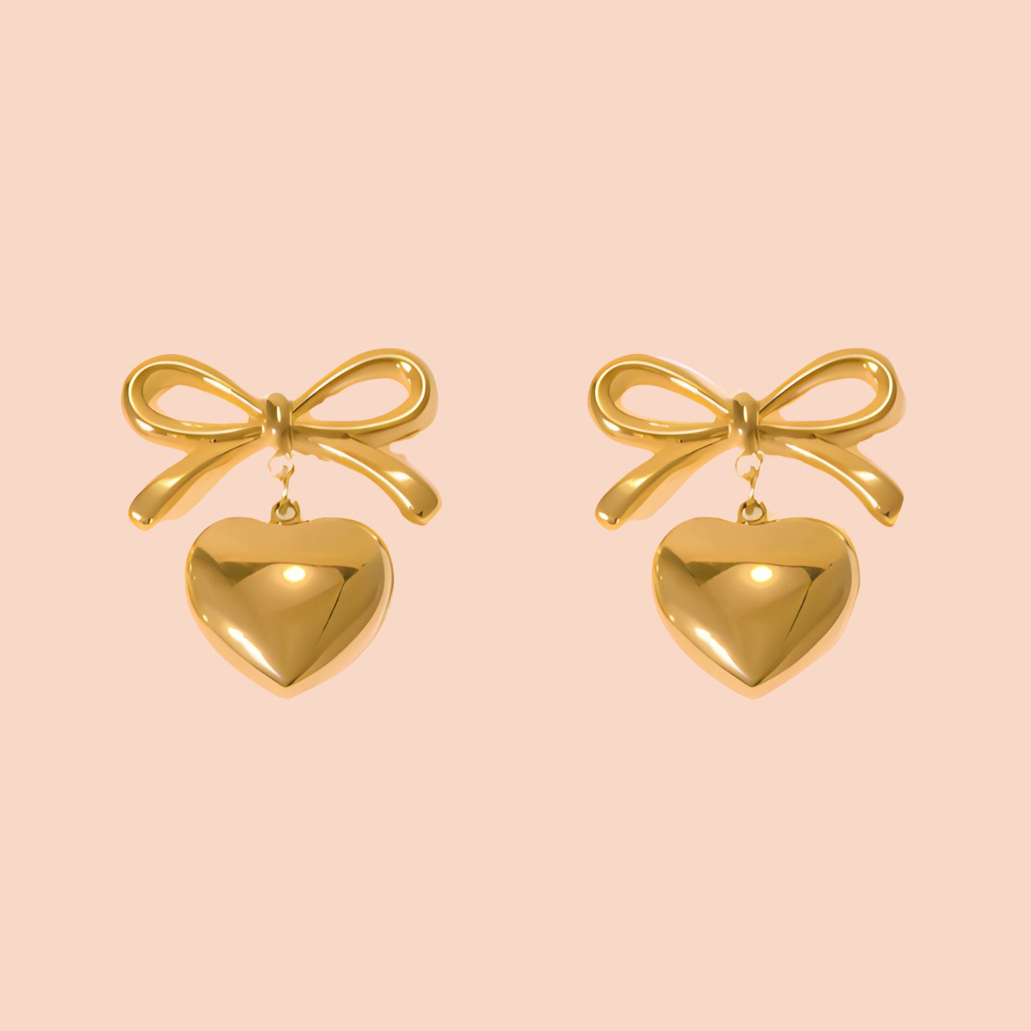 Gold bow and heart earrings on a pink background