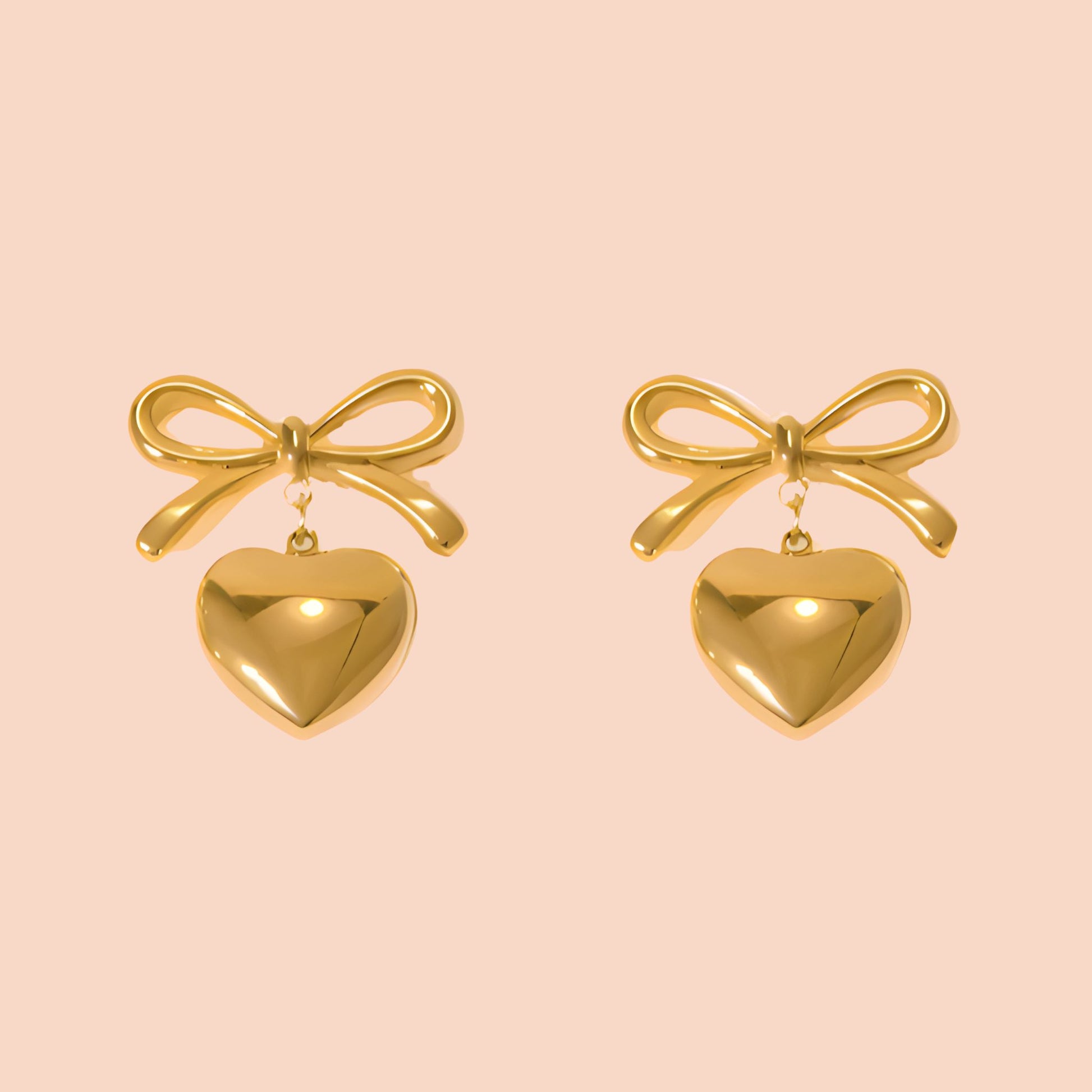 Gold bow and heart earrings on a pink background