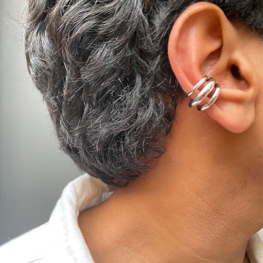 Close-up of an ear with a silver earring and gray hair.