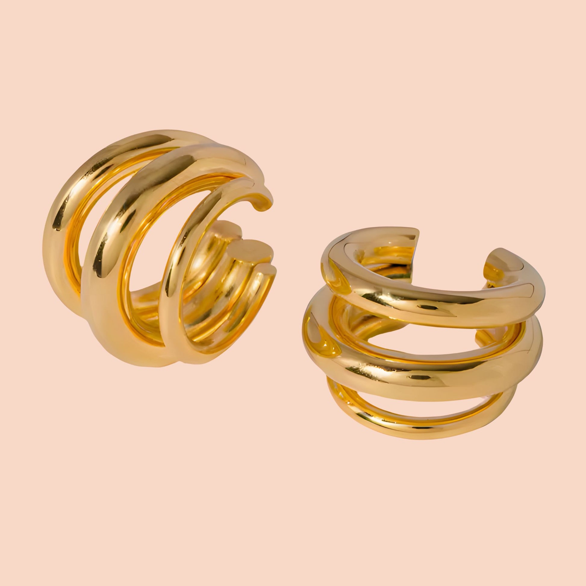 Pair of gold spiral earrings on a beige background