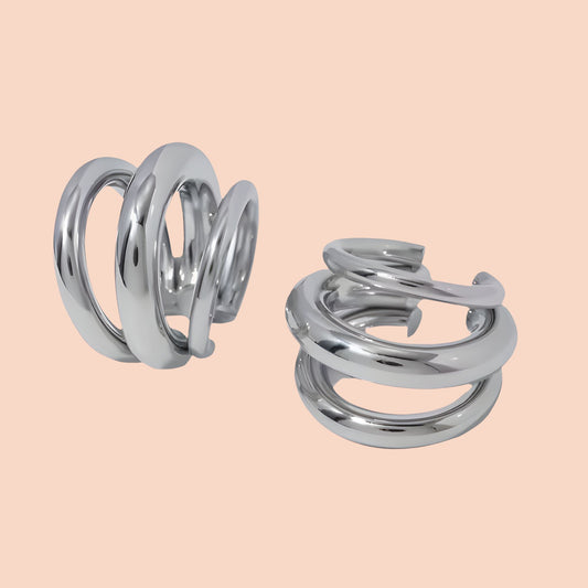 Pair of silver spiral earrings on a beige background