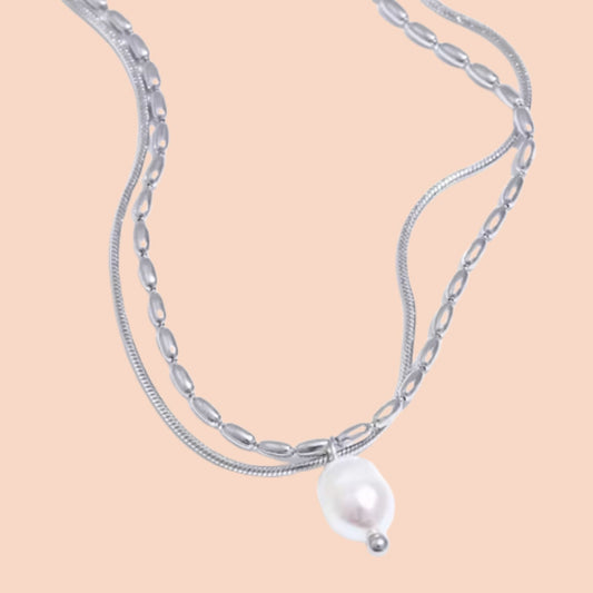 Silver chain necklace with a pearl pendant on a beige background