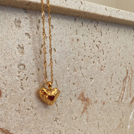 Gold heart-shaped pendant necklace on a textured surface