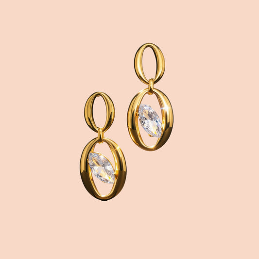 Gold earrings with clear gemstones on a beige background
