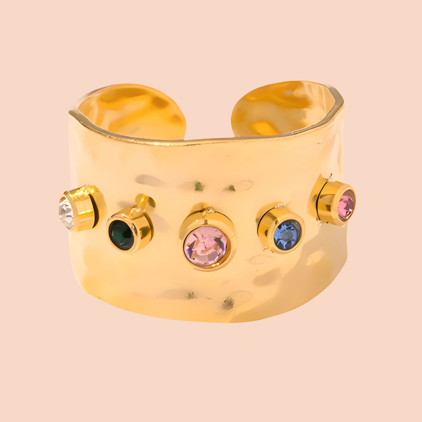 Gold ring with colorful gemstones on a beige background