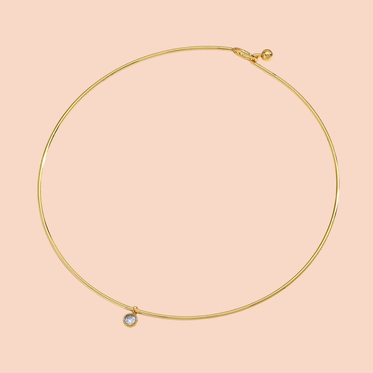 Gold necklace with a small gemstone on a pink background