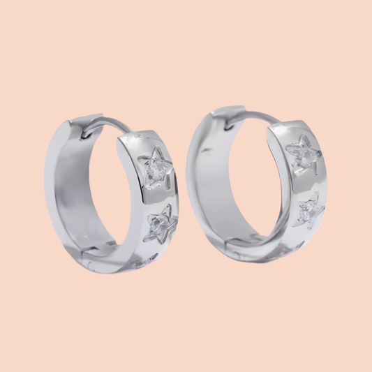 Silver hoop earrings with star designs on a beige background