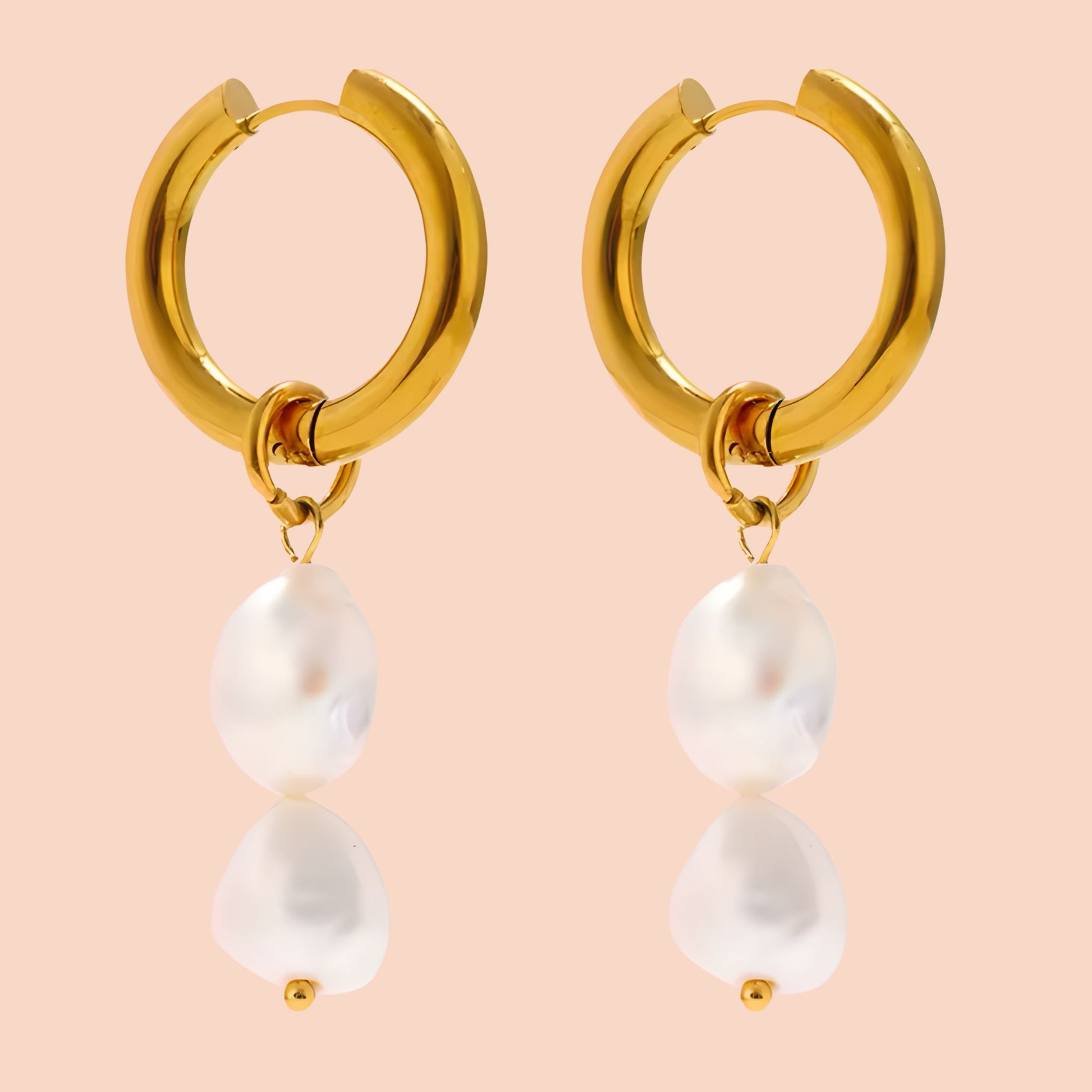 Gold hoop earrings with pearl drops on a peach background