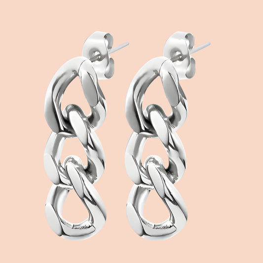 Silver chain link earrings on a light pink background