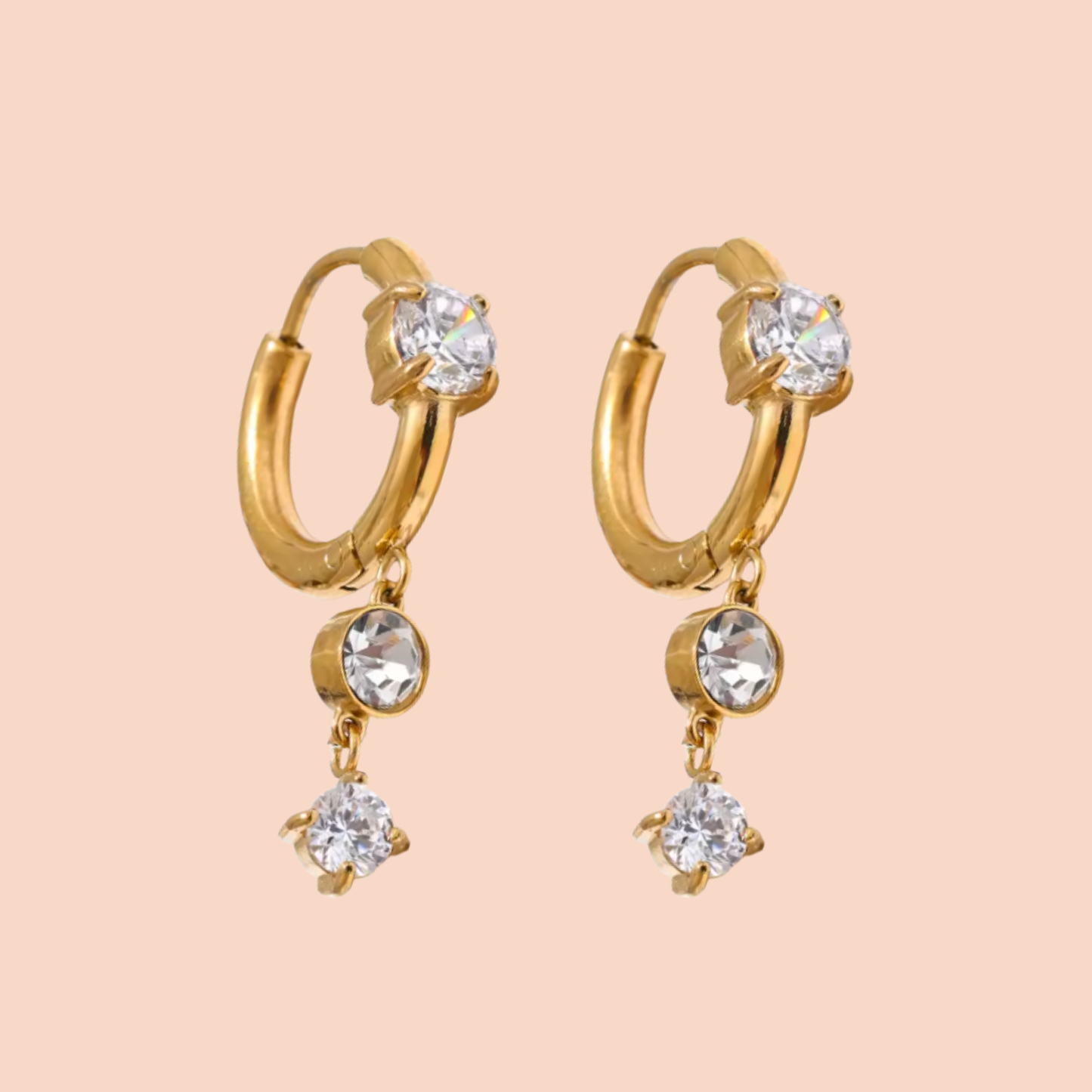Gold hoop earrings with crystal drops on a beige background