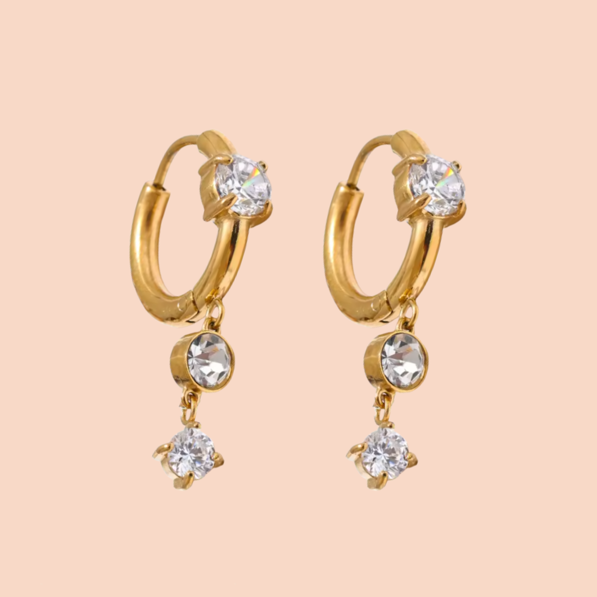 Gold hoop earrings with crystal drops on a beige background