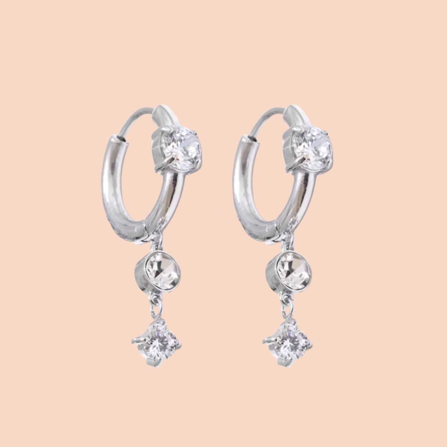 Silver hoop earrings with clear gemstones on a beige background