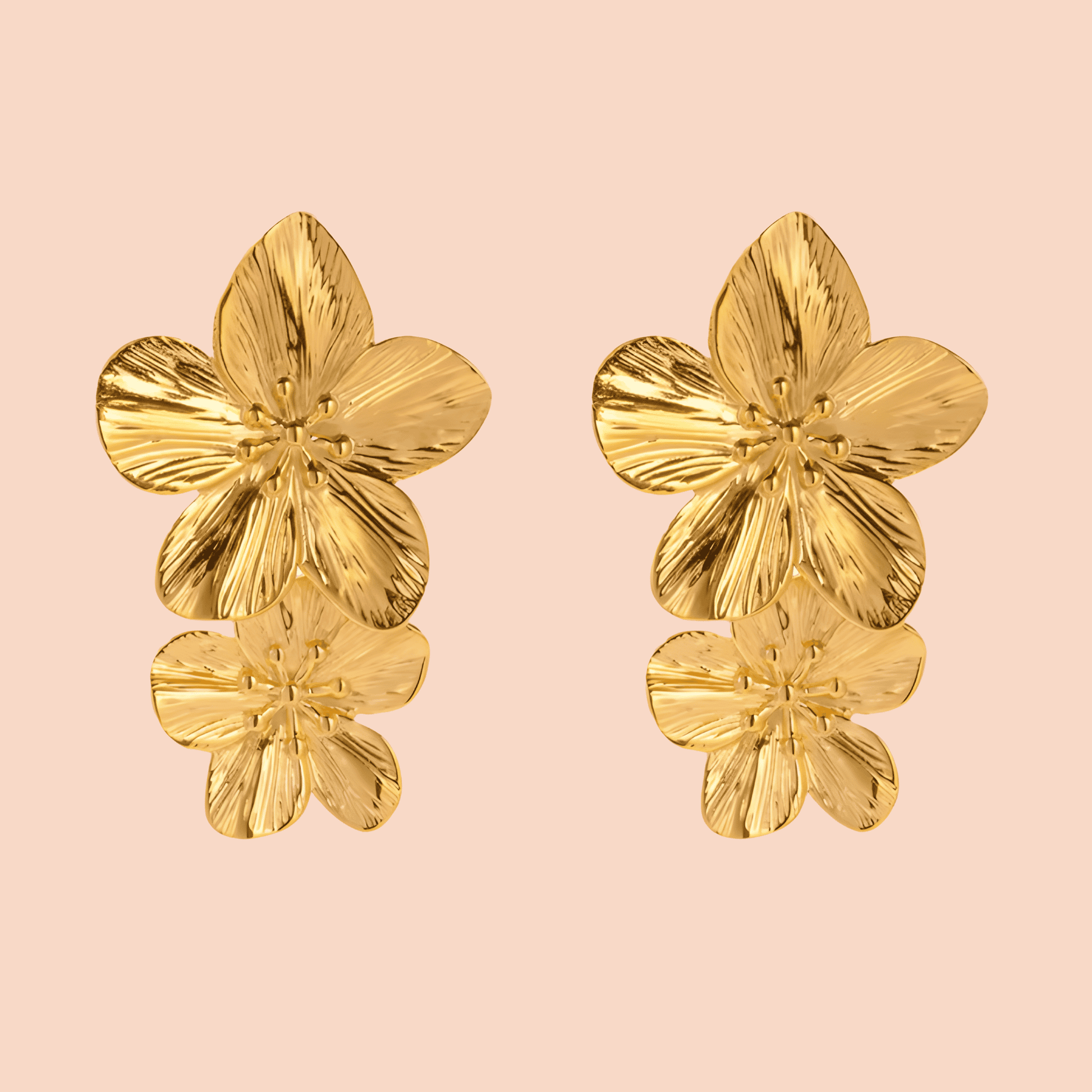 Gold floral earrings on a pink background