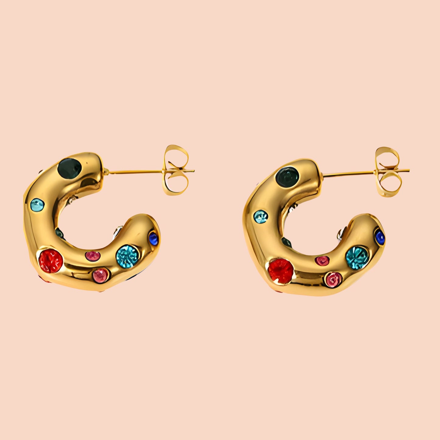 Gold hoop earrings with colorful gemstones on a beige background