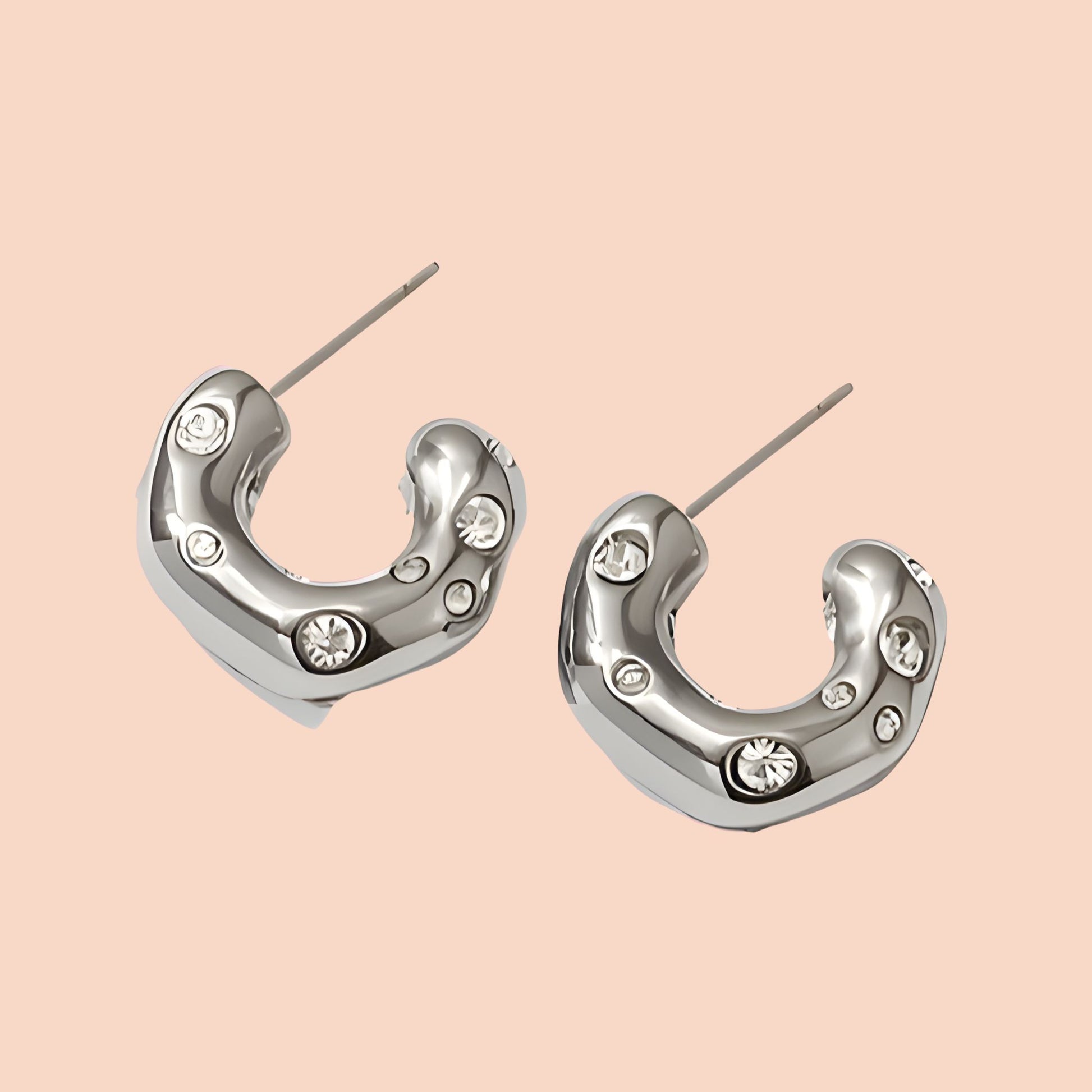 Silver hoop earrings with embedded crystals on a beige background