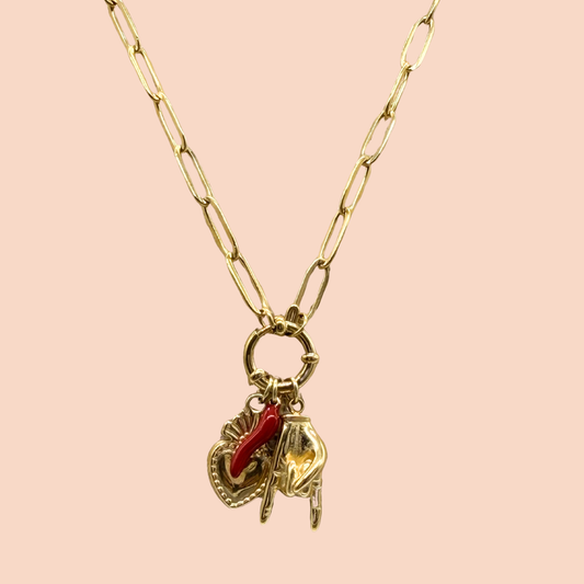 Gold necklace with a red and gold pendant on a pink background