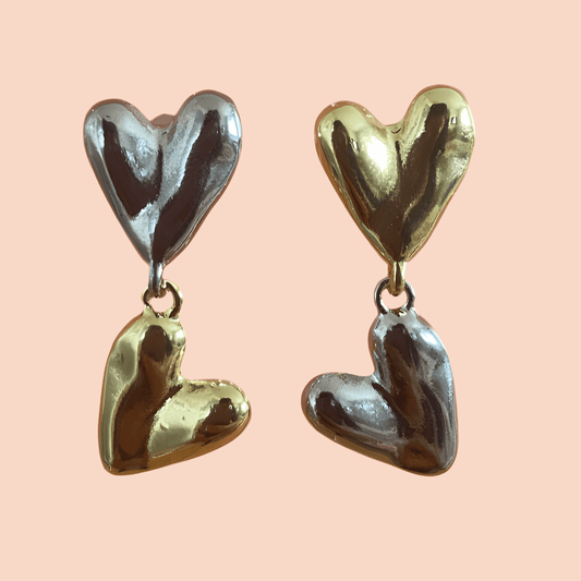 Heart-shaped earrings in gold and silver on a pink background