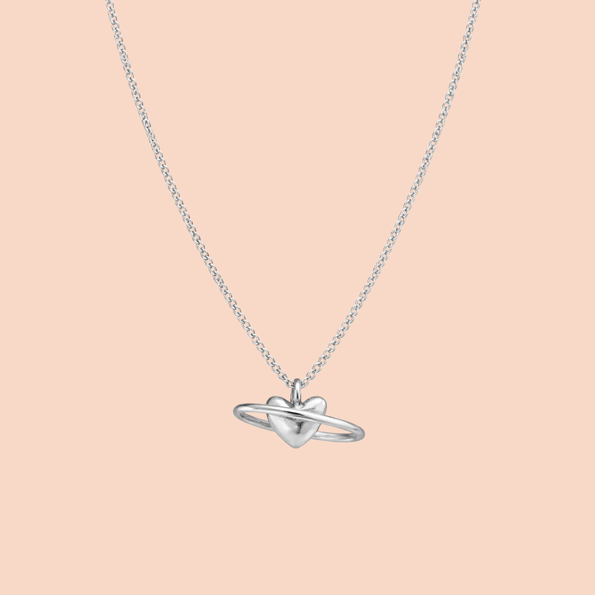 Silver necklace with a heart-shaped pendant on a light pink background