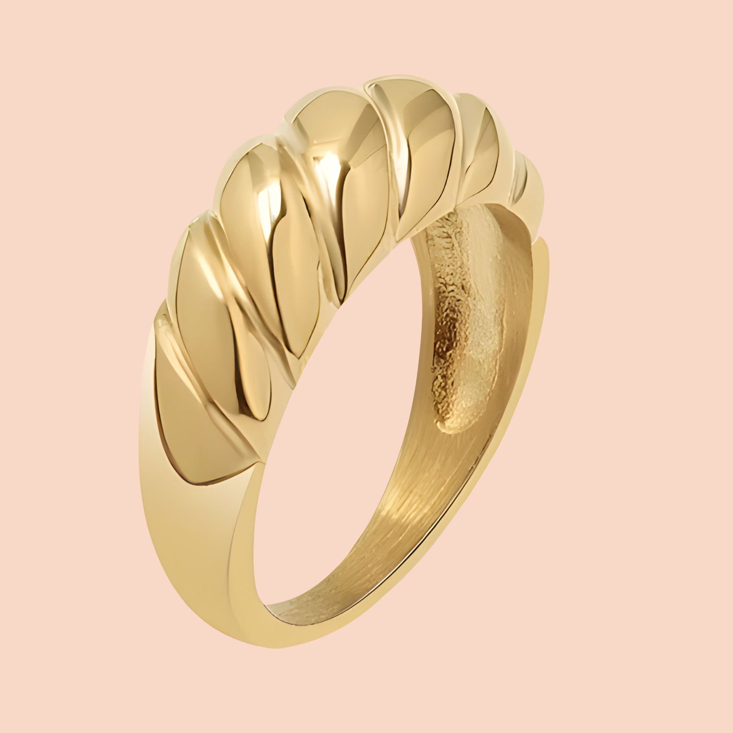 Gold ring with a textured design on a pink background